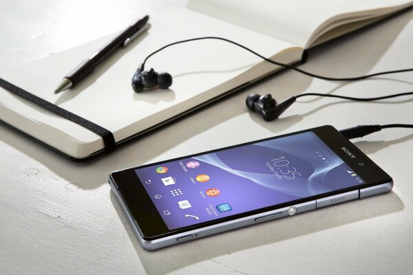 Smartphone sony con auricolari, penna e blocco note