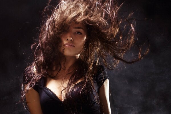 The wind developing the disheveled hair of a brown-haired woman