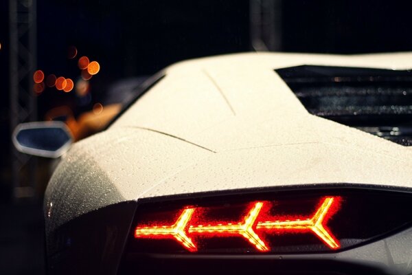 Vista nocturna de las dimensiones traseras del Lamborghini blanco