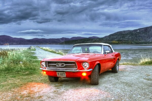 Red mustang by the lake in cloudy weather