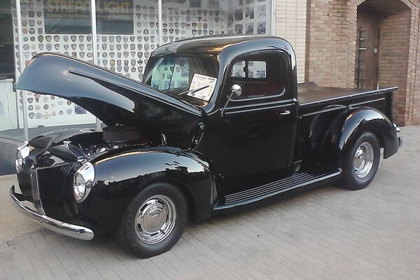 In the photo, an old car with an open hood