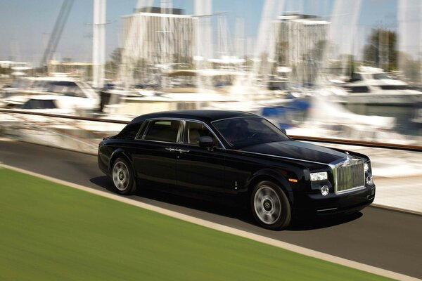 Black Rolls Royce riding on the background of yachts