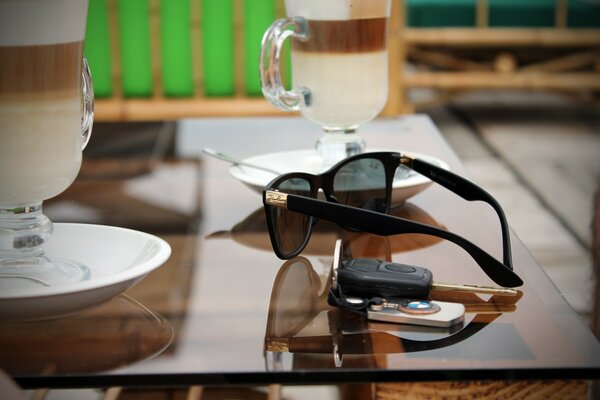 Ein Tisch, auf dem Becher stehen, eine Brille und Schlüssel mit einem BMW-Schlüsselanhänger liegen