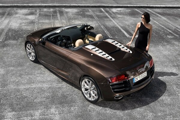 A girl in a black dress near a brown car