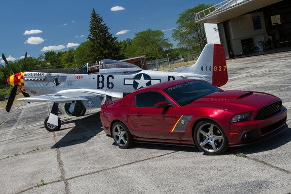 Red Ford sports car next to the plane on the road