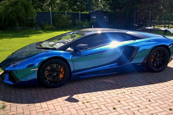 A mirrored Lamborghini stands on a sunny street