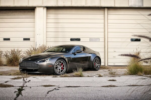 El coche gris oscuro de Aston Martin en el fondo de garajes cerrados