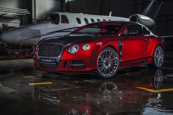 Красная Bentley mansory около самолёта