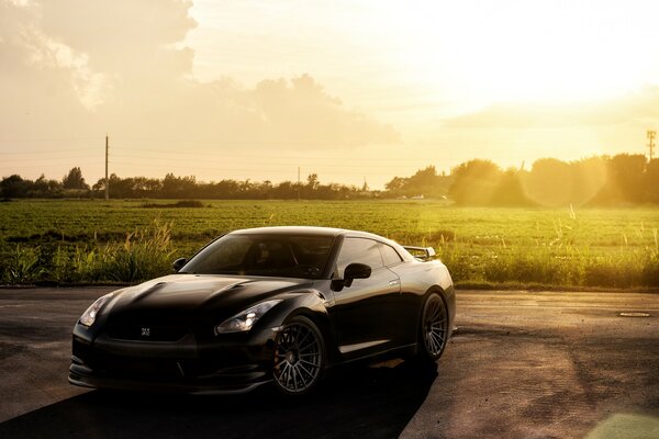 Dunkler Nissan auf einem Feld unter strahlender Sonne