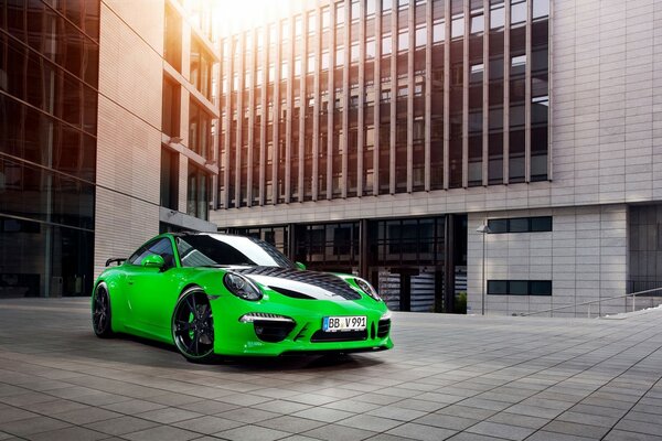 Porsche verte avec inserts noirs sur le fond d un bâtiment moderne dans les rayons du soleil
