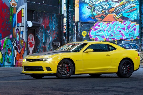 Coche Corvette Camaro amarillo contra la pared con grafito