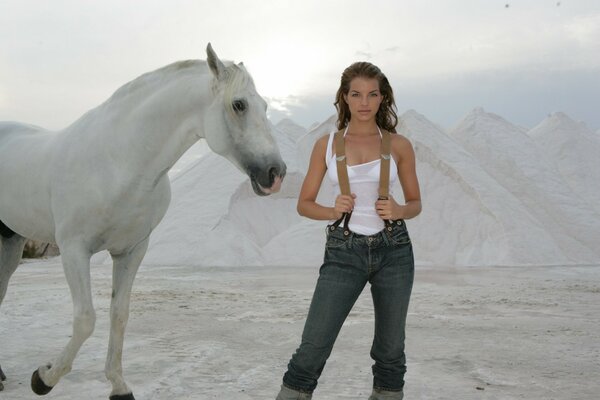 Yvonne Katierfeld sullo sfondo delle montagne bianche accanto al cavallo bianco