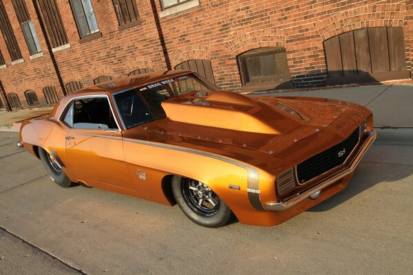 A gold-colored car on the background of a brick building