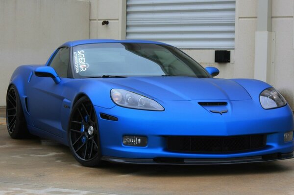 Corvette azul contra un edificio blanco