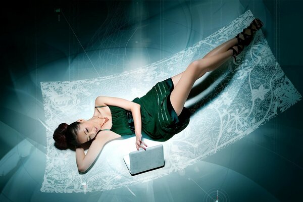 Beautiful girl in a green dress with a laptop