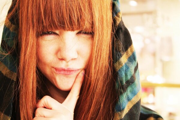 A red-haired girl in a hood smiles