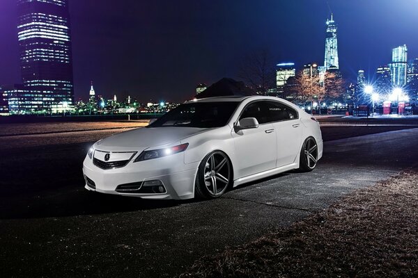 Honda Acura blanco con ruedas tuneadas en el fondo de la ciudad