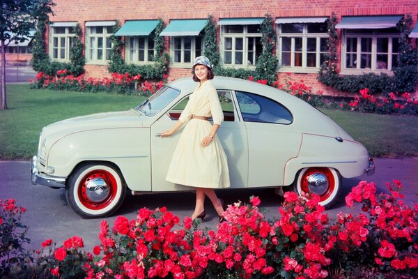 Belle fille et voiture rétro parmi les fleurs