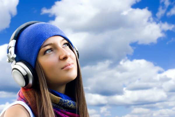 Hermosa chica en los auriculares contra el cielo