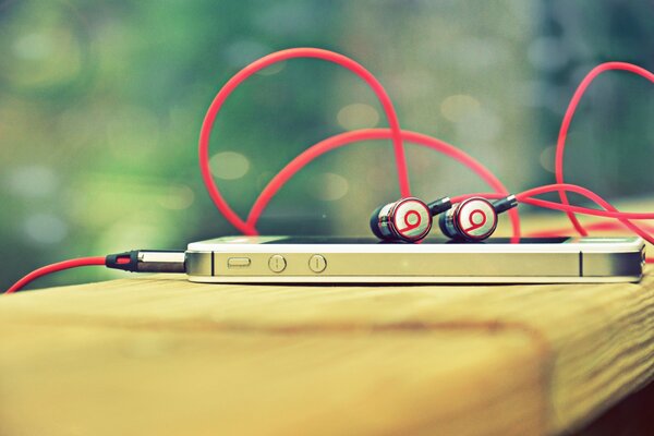 IPhone avec des écouteurs beats repose sur une surface en bois