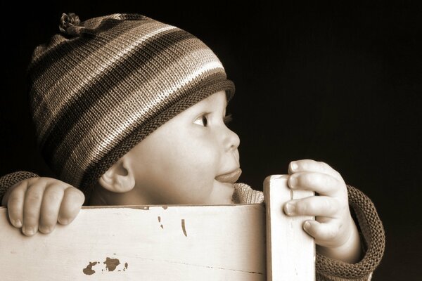 A kid in a striped hat in profile on a black background