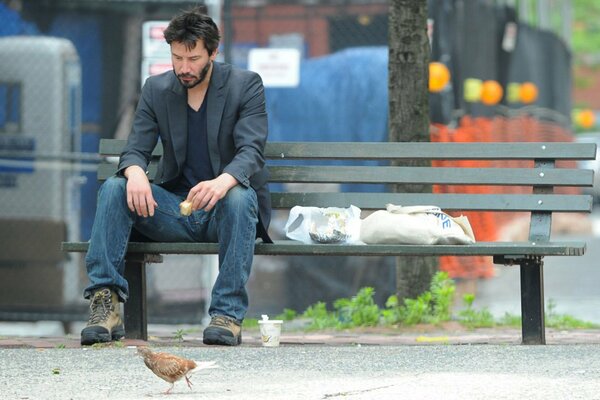 Keano Reeves dines on a bench