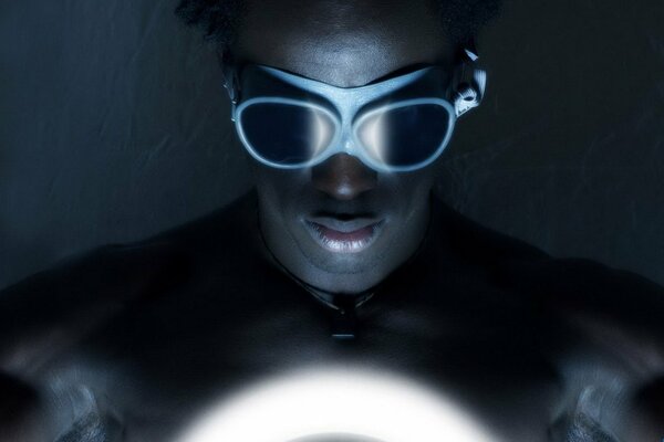 A dark-skinned guy in safety glasses looks at the light