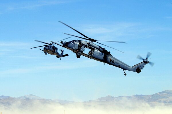 Dos helicópteros vuelan sobre las montañas en la neblina