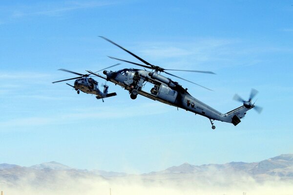 Due elicotteri sorvolano le montagne nella foschia