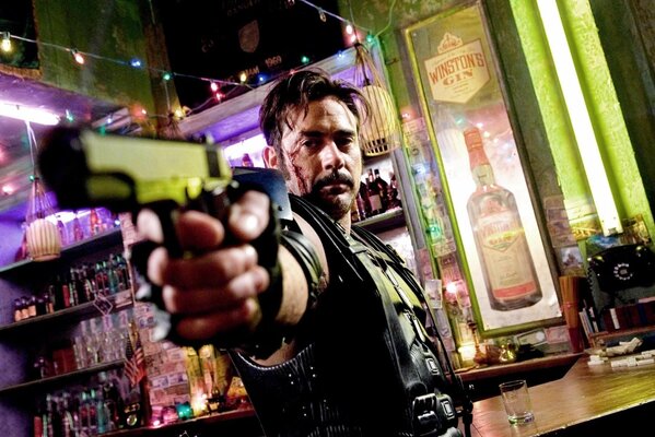 A man with a gun in a bar, near the bar counter