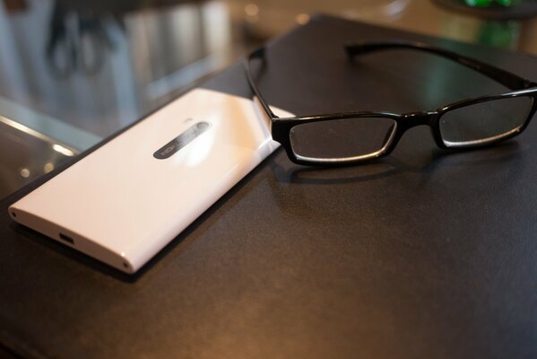 Glasses with a white smartphone on the edge of the table