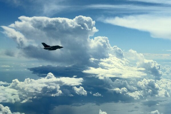 Ein Militärflugzeug fliegt in den Himmel unter den Wolken