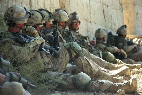 Vacanciers assis près d un mur de soldats en uniforme