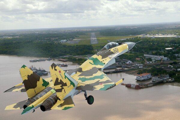 A camouflaged su-35 aircraft is brought to the airfield for landing