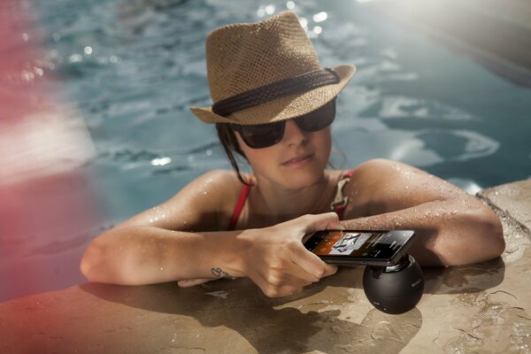 A girl in the pool holds a phone in her hand