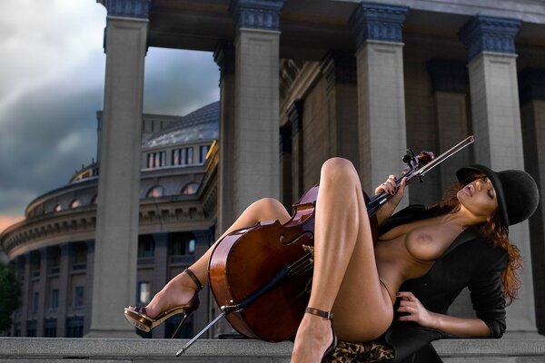 Nude girl with a musical instrument between her legs