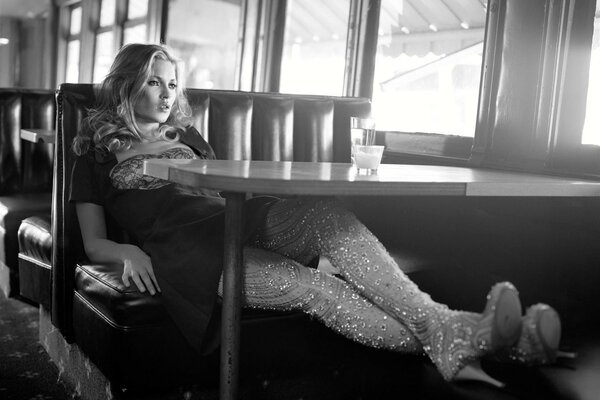 A girl in a dress is resting on the sofa near the table