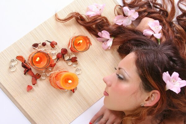 The girl is lying with candles and flowers in her hair