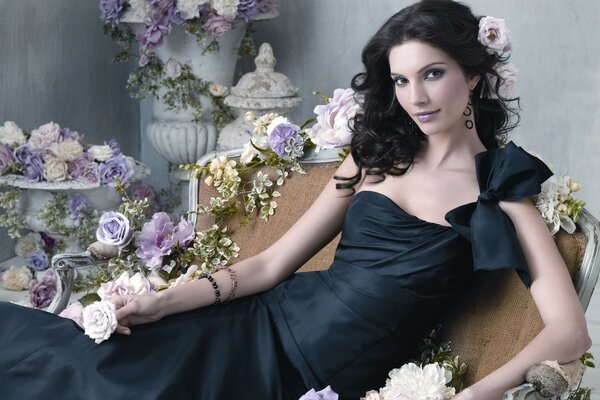 A girl in a black dress on a background of flowers