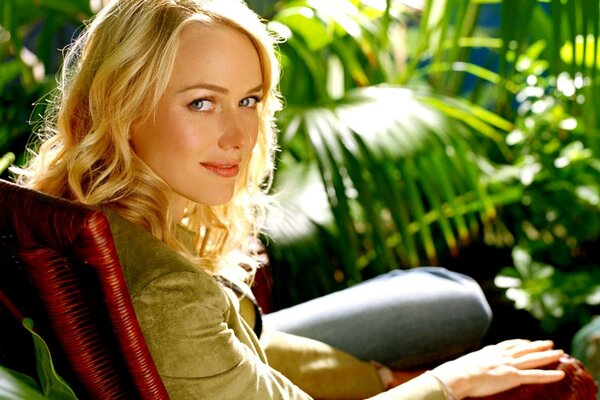 Actress Naomi Watts in a chair among plants