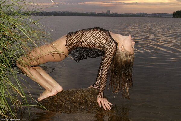 Chica desnuda en una camisa de malla, sexy posando en el fondo del río