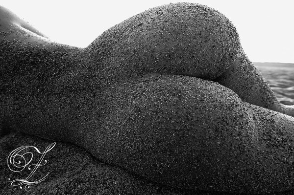 Schwarz-Weiß-Foto von nacktem Arsch im Sand in Nahaufnahme