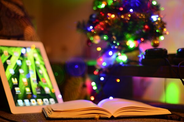 Weihnachtsbaum im Zimmer. Tablet und Buch auf dem Tisch