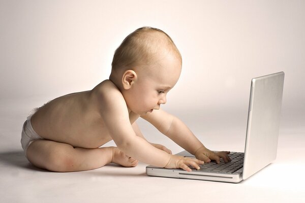 A baby is typing on a laptop on a white background