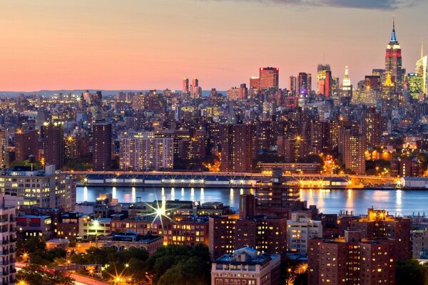 Lights of Manhattan skyscrapers on the background of sunset