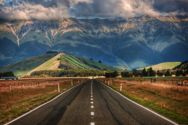 Route entourée de champs avec vue sur les collines et les montagnes de la Nouvelle-Zélande