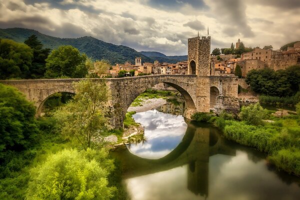 Riflessione di un ponte di pietra nel fiume Fluvia