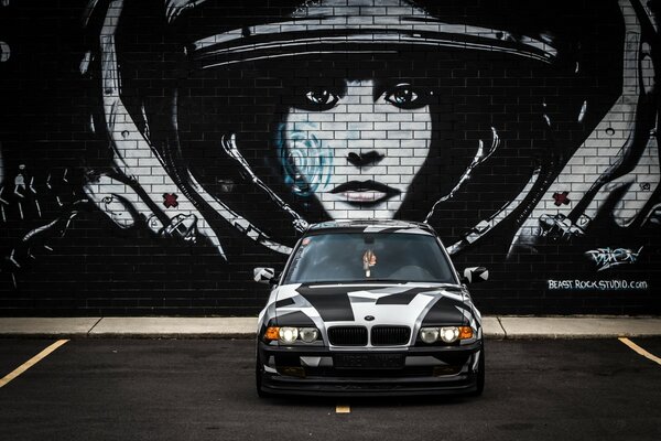 BMW car painted arctic camouflage on a brick wall background