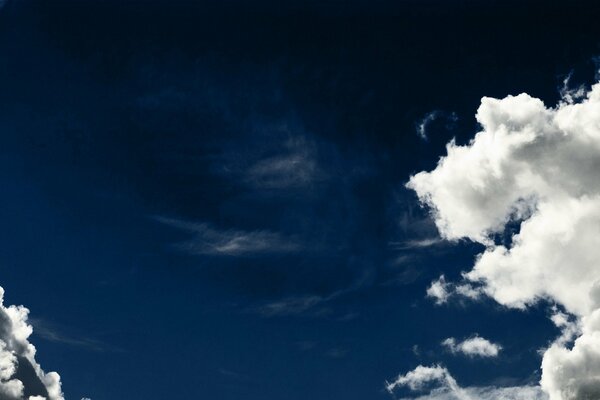 Dunkler blauer Himmel mit weißen Wolken