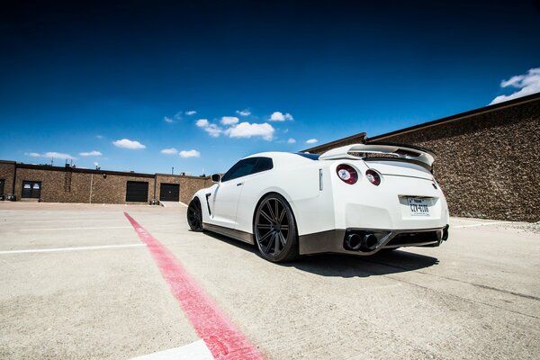 White Nissan r35 rear view against the sky and clouds